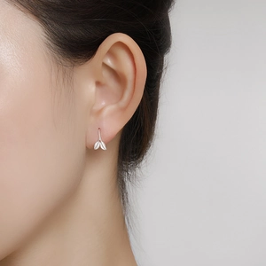 Close-up of elegant S999 sterling silver ginkgo leaf stud earrings on model's ear