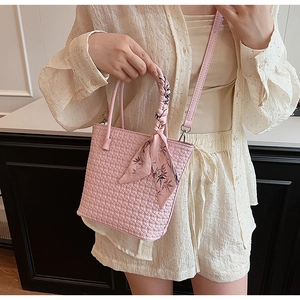 Detail of pink woven bucket bag with patterned silk scarf handle and leather strap