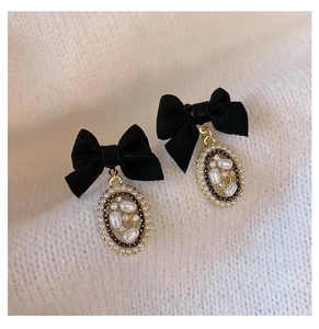 Macro detail of French vintage bow earrings with pearls on white knit fabric background