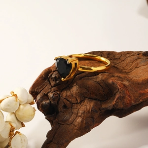 Detailed view of a gold heart-shaped ring with a black gemstone on rustic wood