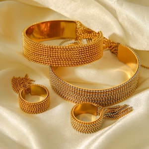 Detailed view of beaded texture and gold metallic tassels on open bangles and rings