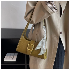 Detail of olive green crocodile texture underarm bag with silk scarf and gold buckle