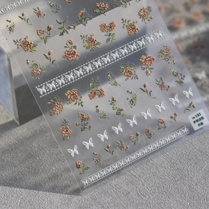 Vue macro des stickers ongles 3D en relief avec fleurs vintage et papillons blancs