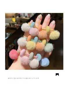 Dettaglio di tre elastici per capelli con pompon colorati e dischi in toni macaron