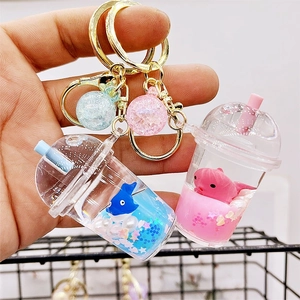 Close-up of a blue acrylic milk tea cup keychain with a floating shark and gold metal hardware