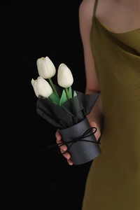 Detailed view of three white PU tulips in a black cylinder gift box with ribbon
