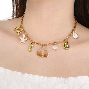 Detail of 18K gold-plated necklace with ocean charms on a model with white clothing