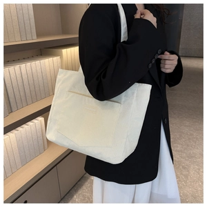Close-up of beige corduroy tote bag with V-shaped pocket and XINRUI GOOD label