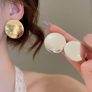 Détail macro de boucles d'oreilles rondes en métal brillant aux finis or et argent polis
