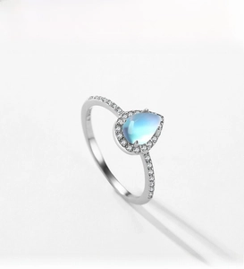 Detailed close-up of pear-shaped moonstone ring with sparkling halo and pavé silver band