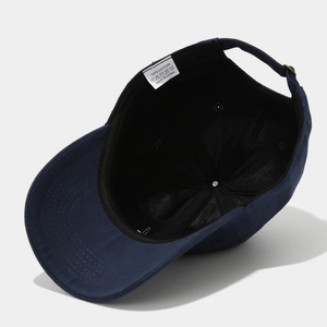 Close-up of internal wash label on 100% cotton navy blue baseball cap showing quality