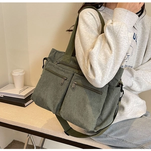 Detail shot of the corduroy texture and zipper pocket on a green shoulder bag
