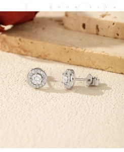 Detailed close-up of round moissanite halo stud earrings on a textured stone surface