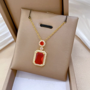 Macro detail of rectangle red ruby pendant necklace with zircon halo in golden finish