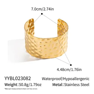 Detailed view of wide gold cuff bracelet featuring a textured hammered finish and open design