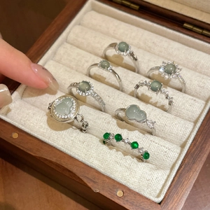 Detail of silver rings with green jade stones in a wooden jewelry box for women