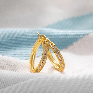Macro detail of 18K gold large hoop earrings with micro-paved sparkling zircon stones