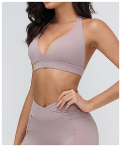 Dettaglio del set yoga rosa con top a V allacciato al collo e leggings a vita incrociata