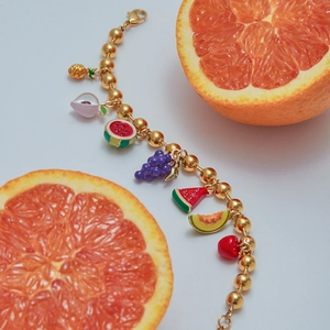 Close-up of gold beaded bracelet with colorful fruit charms and lobster clasp detail