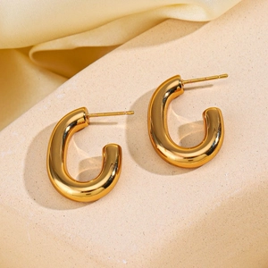 18K gold plated stainless steel hollow oval hoop earrings on beige stone and silk background