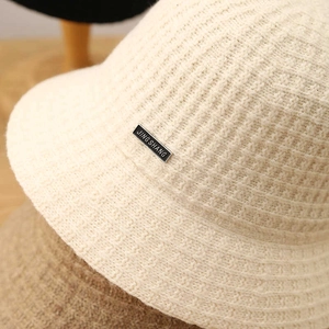 Macro detail of breathable beige wool knit bucket hat with textured waffle pattern
