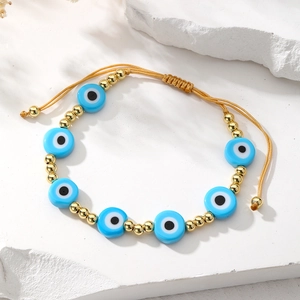 Detailed macro of Evil Eye bead and golden spacers on adjustable braided bracelet