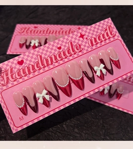 Detail of handmade red and pink press-on nails with 3D bows and pearls in size M packaging