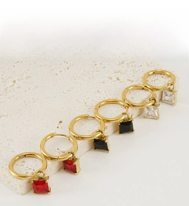 Detailed view of three pairs of golden hoop earrings with square-cut zircon stones