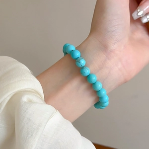 Macro detail of elastic beaded bracelet with sky blue turquoise stones on model wrist