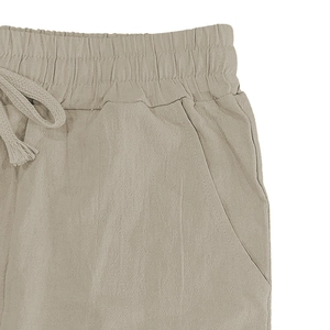 Detail of khaki linen trousers featuring an elastic waistband with adjustable drawstring