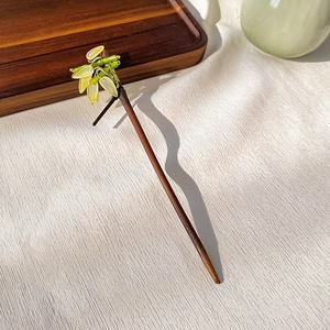 Detailed view of traditional Chinese hair pin with carved flower and wood texture