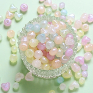 Close-up of pastel mixed heart and round acrylic beads in a glass bowl for DIY jewelry