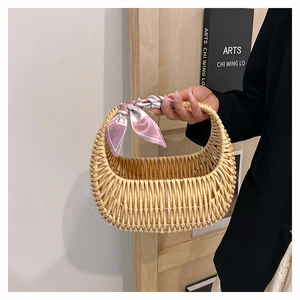 Detail of woven rattan handbag with pink printed silk scarf handle and half-moon design