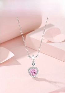 Macro detail of S925 silver necklace featuring a pink heart stone and a diamond crown pendant