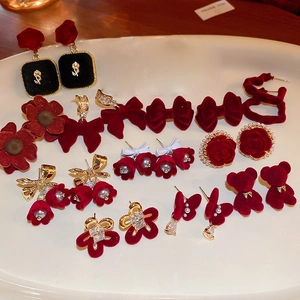Macro display of diverse red flocked flower and pearl earrings with golden accents