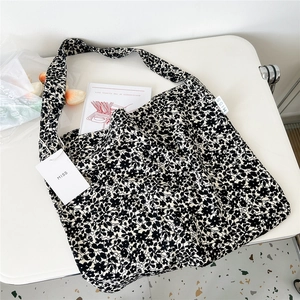 Detailed close-up of a floral canvas tote bag with Miss tag on a white aesthetic desk