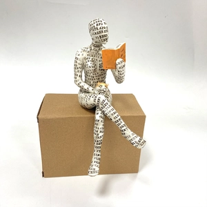 Detail of reading woman figurine with letter patterns and a small cat on resin sculpture