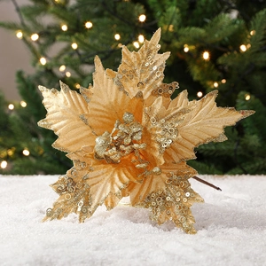 Golden artificial Christmas poinsettia flower with sequins on snow background decoration