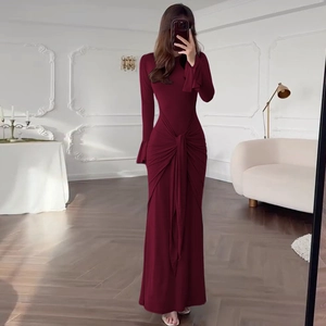 Détail d'une robe longue bordeaux à manches longues avec nœud à la taille et poignets évasés