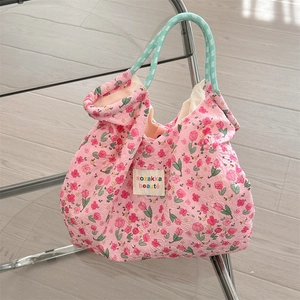 Close-up of pink tulip print canvas tote with green rope handles on a chair