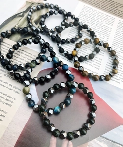 Stacked natural tiger eye and hematite beaded bracelets on a magazine backdrop