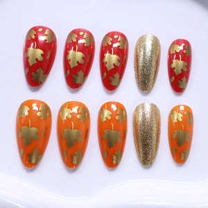 Almond press-on nails set with red and orange colors, maple leaf patterns and gold glitter