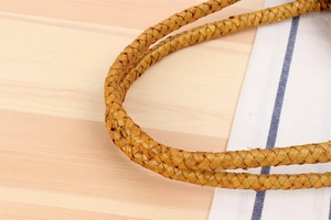 Close-up of woven straw handle on rustic shoulder bag featuring natural fiber texture
