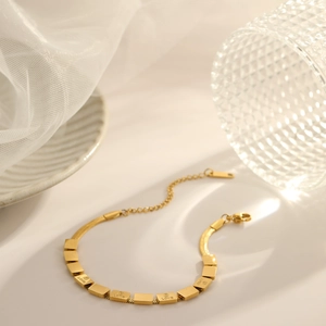 Detail of gold LOVE letter engraved square charms on minimalist stainless steel chain