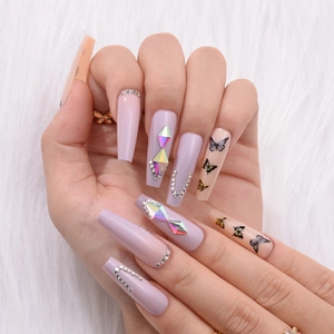 Detail of long ballerina press-on nails with purple matte rhinestones and black butterfly patterns