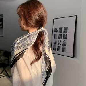 Close-up of blue and white paisley silk scarf used as an elegant hair tie on low ponytail