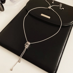 Silver zirconia circle tassel necklace displayed on black leather background with soft light