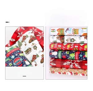 Detailed view of Christmas wrapping paper rolls featuring red snowflakes and reindeer patterns