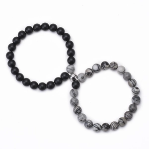 Close-up of magnetic heart clasp connecting matte black and white turquoise stone bracelets