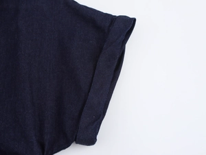 Détail des poignets roulés à double surpiqûre sur une robe midi en denim bleu foncé texturé